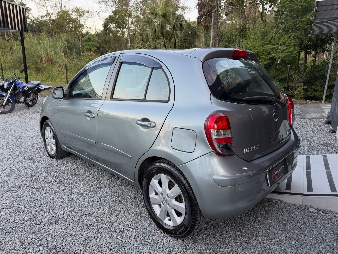 Nissan March cinza visto pela traseira